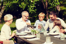 54866256 - family, generation, technology, home and people concept - happy family with tablet pc computers sitting at table in summer garden