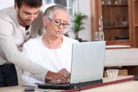11605393 - young man helping a senior with a laptop computer